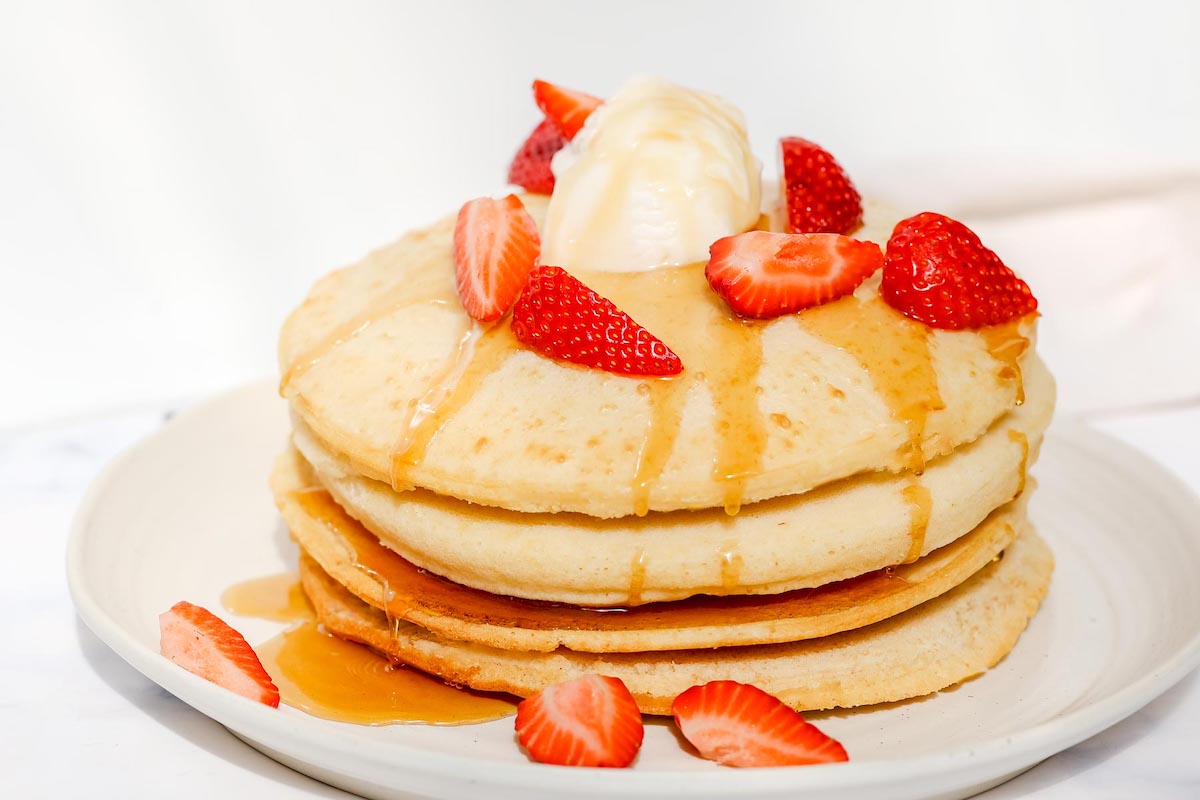 Air fryer pancakes topped with strawberries and syrup.