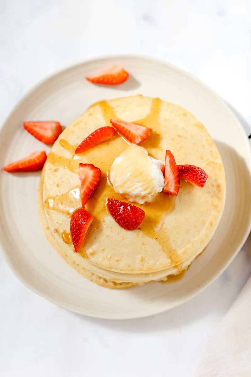 Air fryer pancakes topped with strawberries and syrup.