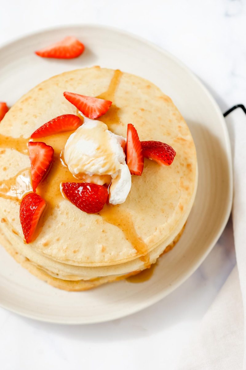 Air fryer pancakes topped with strawberries and syrup.