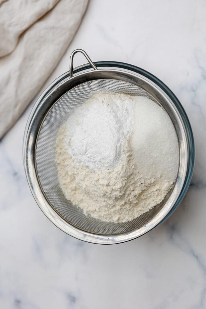 Sifting flour, sugar, and baking powder.