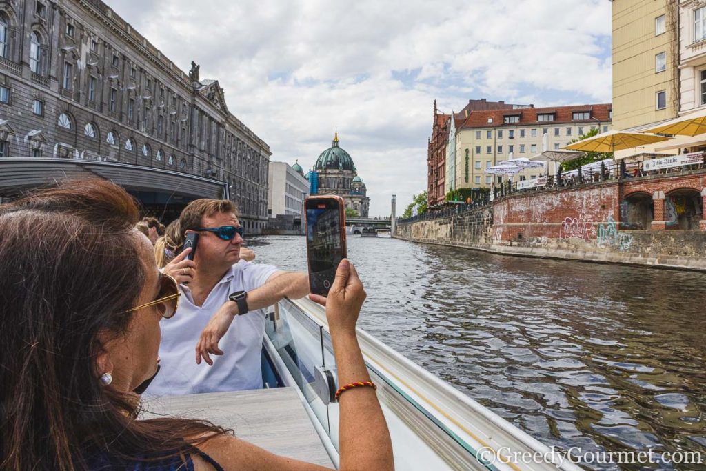 A woman on a bout taking a video of the surrounding area of berlin.