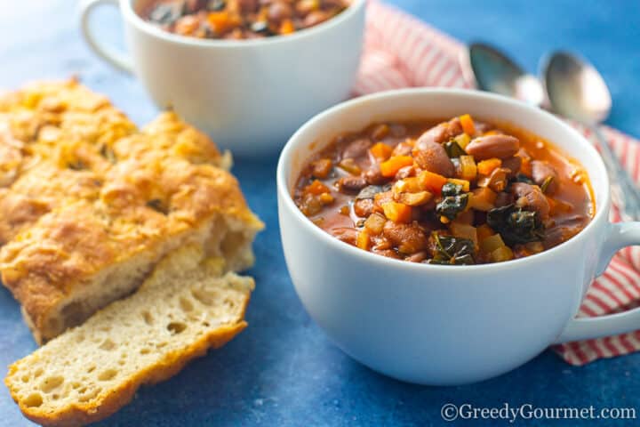 cup of soup next to sliced bread