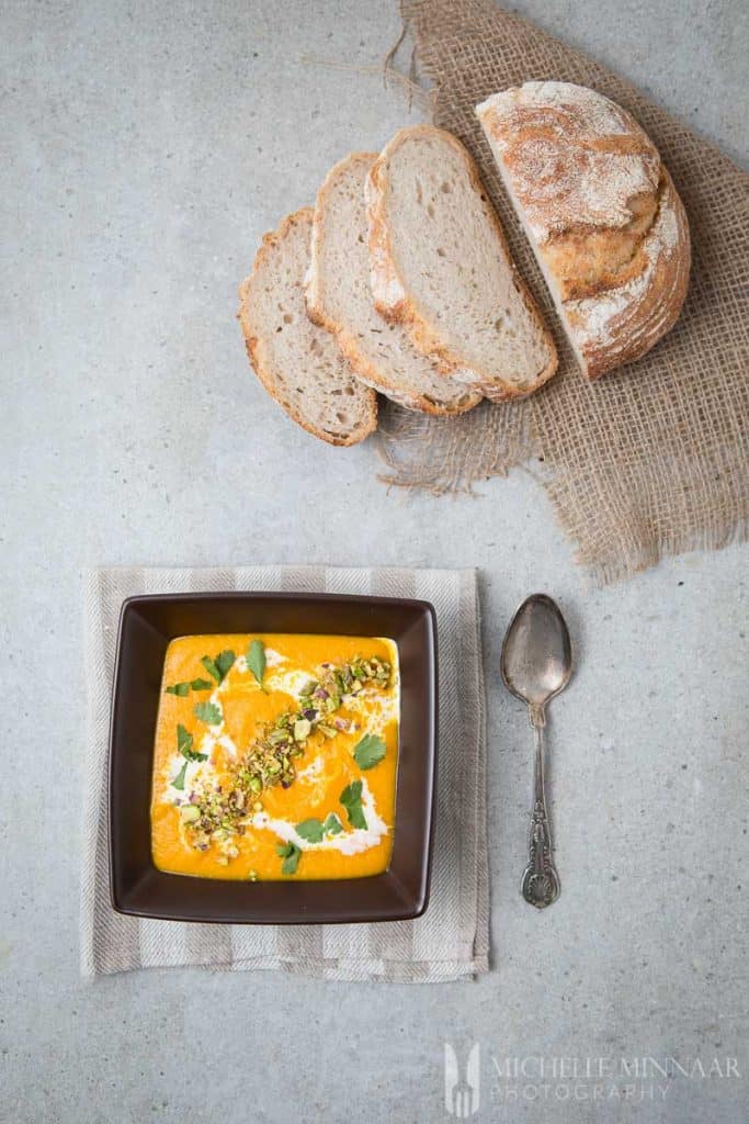 Three slices of bread and a bowl of carrot soup 