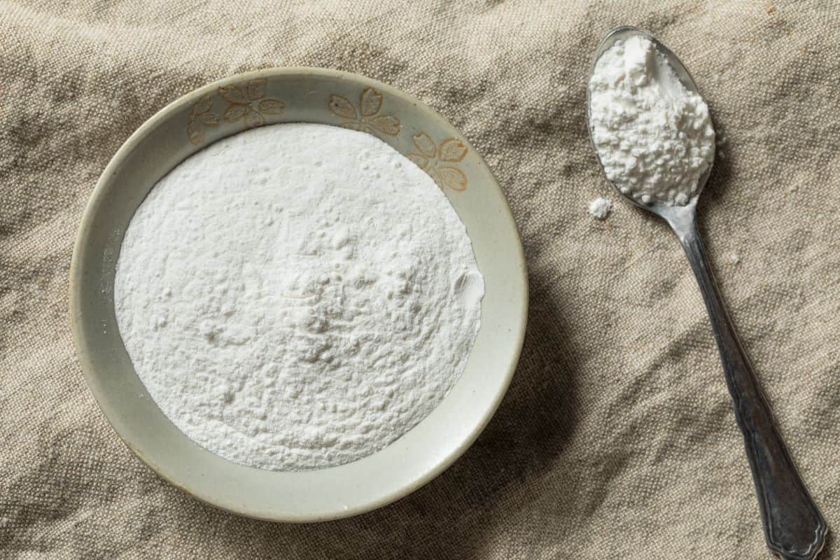 Bowl of cream of tartar powder and a spoon next to it.