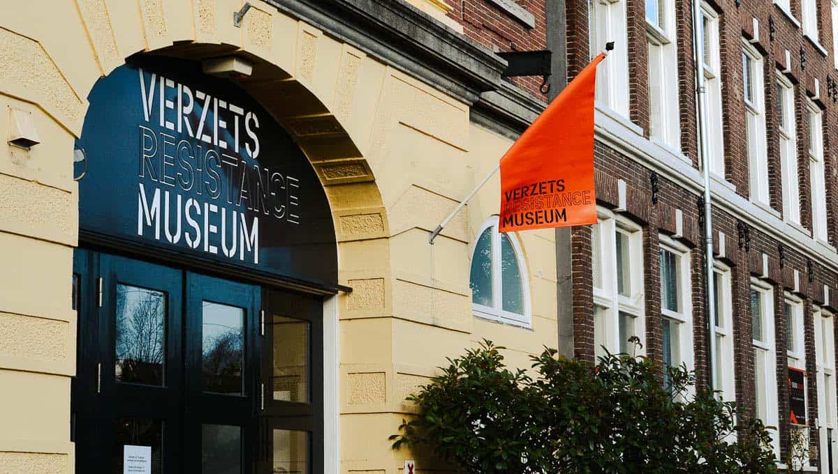 Door to the Dutch Resistance Museum with an orange flag attached to the wall beside it.