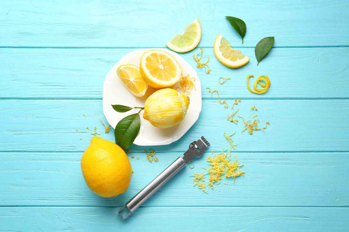 A plate with a lemon that has been zested with the zest on the table around the plate.