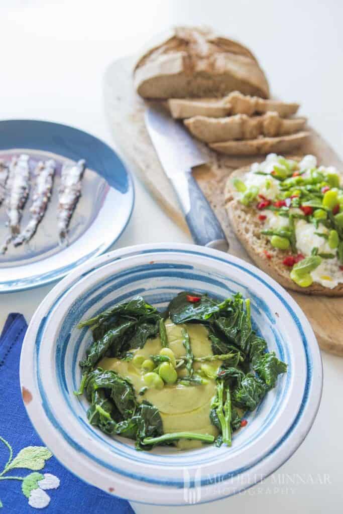 A bowl of macco di fave with some bread and sardines on a plate