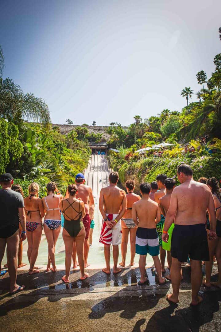 People watching others take a fast water slide down.