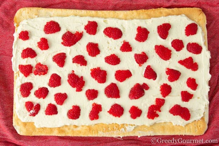 Raspberries lined on top of cream on a vanilla cake