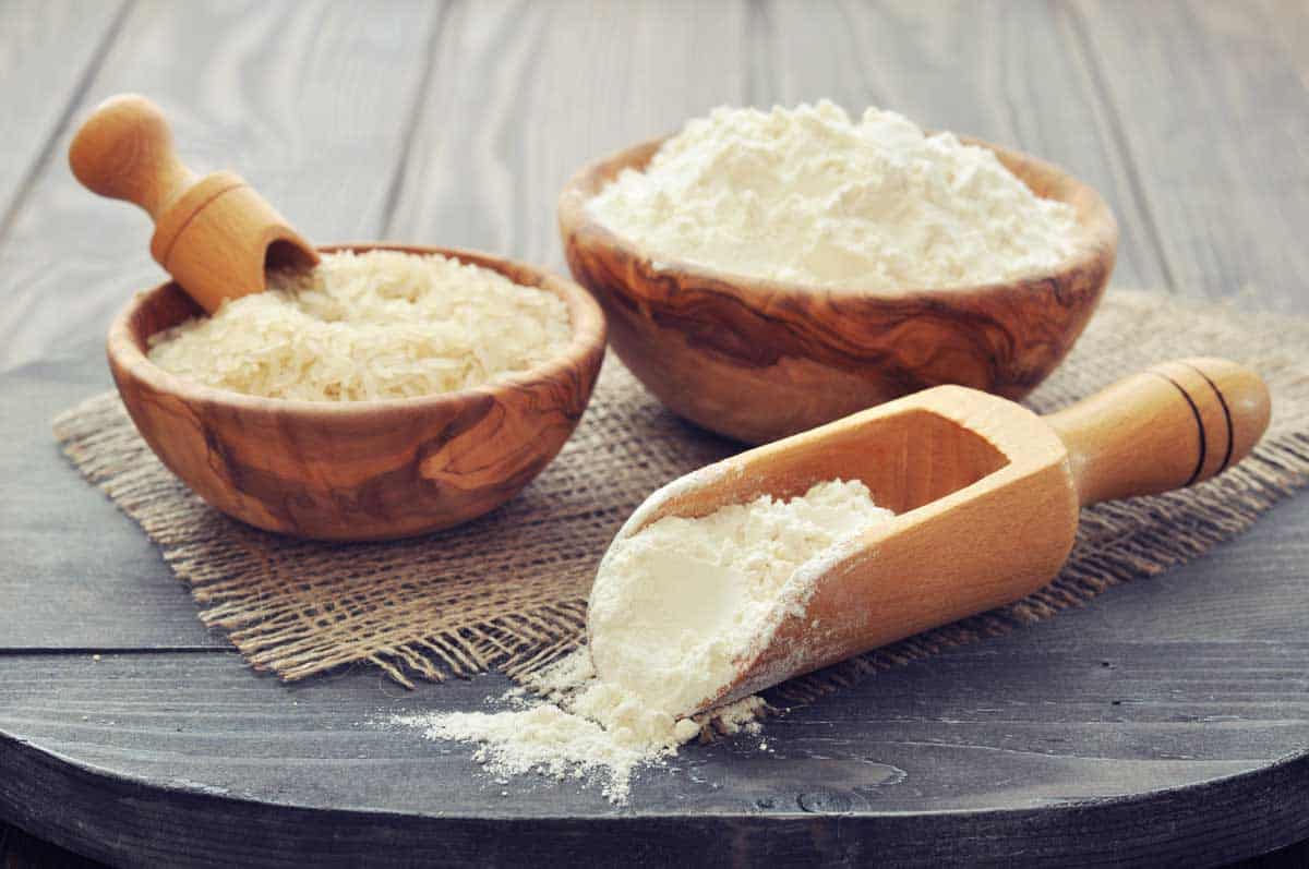 Rice flour spilling out of a wooden sppon to be used as an arrowroot substitute