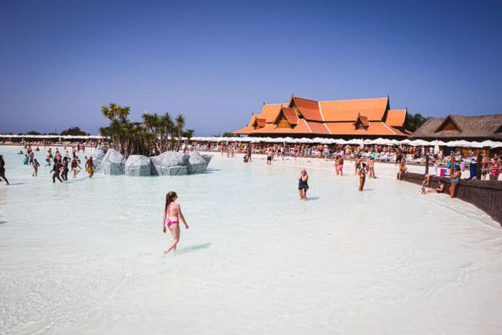 Siam Beach at Siam Park. People walking in shallow water while people sit in the distance.