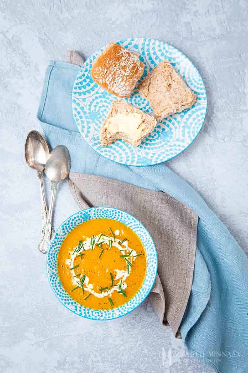 Bowl of orange slimming world butternut squash soup and rolls with buttter