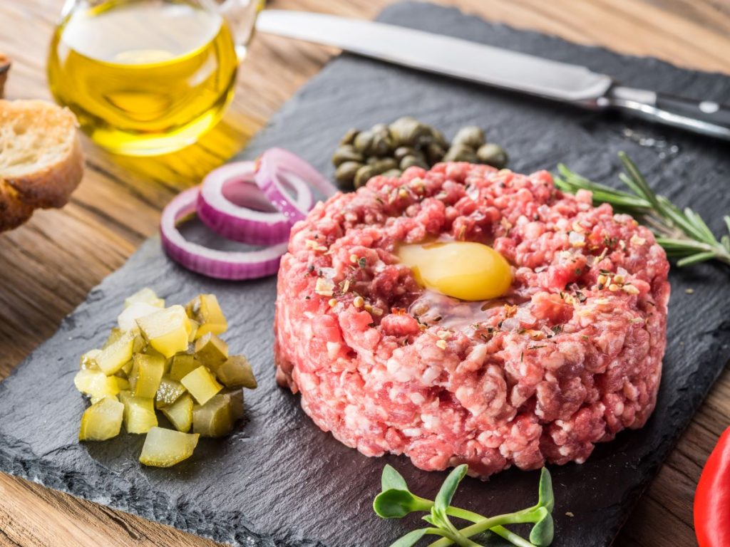 Steak Tartare served with pickles and onion rings.