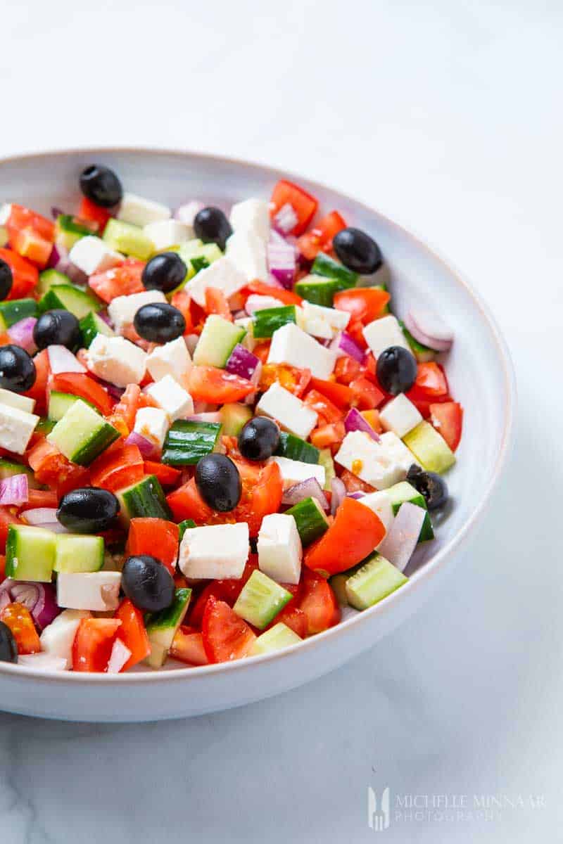 A close up of tomatoes, black olives, feta cheese and peppers