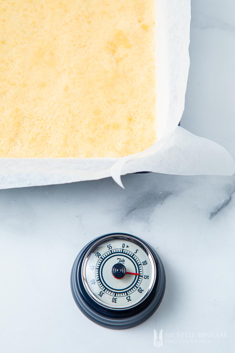 Layered cake in a tin and a timer